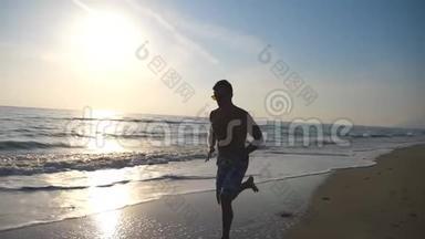 日出时，年轻运动男子沿着海岸快速奔跑的<strong>剪影</strong>。 在沙滩上训练运动员，<strong>海浪</strong>在沙滩上
